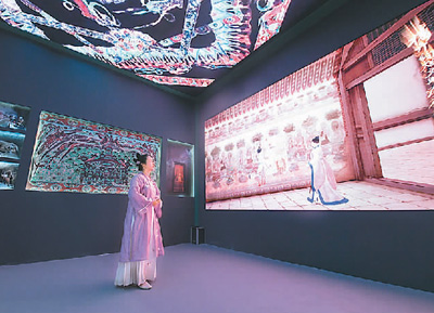 第十九屆中國（深圳）國際文化產(chǎn)業(yè)博覽交易會設(shè)立了“數(shù)字中國——AI時代的文化創(chuàng)新”主題展區(qū)。一批大數(shù)據(jù)、人工智能等技術(shù)應(yīng)用文化企業(yè)參展。數(shù)字化助力中華傳統(tǒng)文化“活”起來，也為現(xiàn)場觀眾帶來了新鮮的觀展體驗(yàn)。   圖為一名身著傳統(tǒng)服飾的觀眾在文博會甘肅展臺觀看數(shù)字敦煌展覽。   新華社記者 梁 旭攝