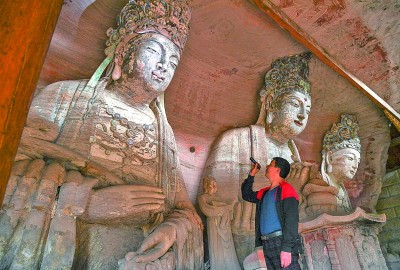 義務(wù)文保員在對重慶市大足區(qū)寶頂鎮(zhèn)香山社區(qū)的佛祖巖摩崖造像進(jìn)行巡查。新華社記者 王全超攝