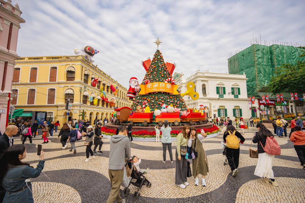 12月12日，游客在澳門議事亭前地的圣誕樹前拍照。新華社記者 朱煒 攝