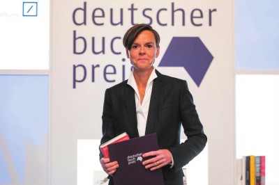     作家安特耶·拉維克·施特魯貝爾在2021年德國圖書獎(jiǎng)?lì)C獎(jiǎng)典禮上手持《藍(lán)色女人》和獲獎(jiǎng)證書。攝影：托馬斯·洛內(nèi)斯